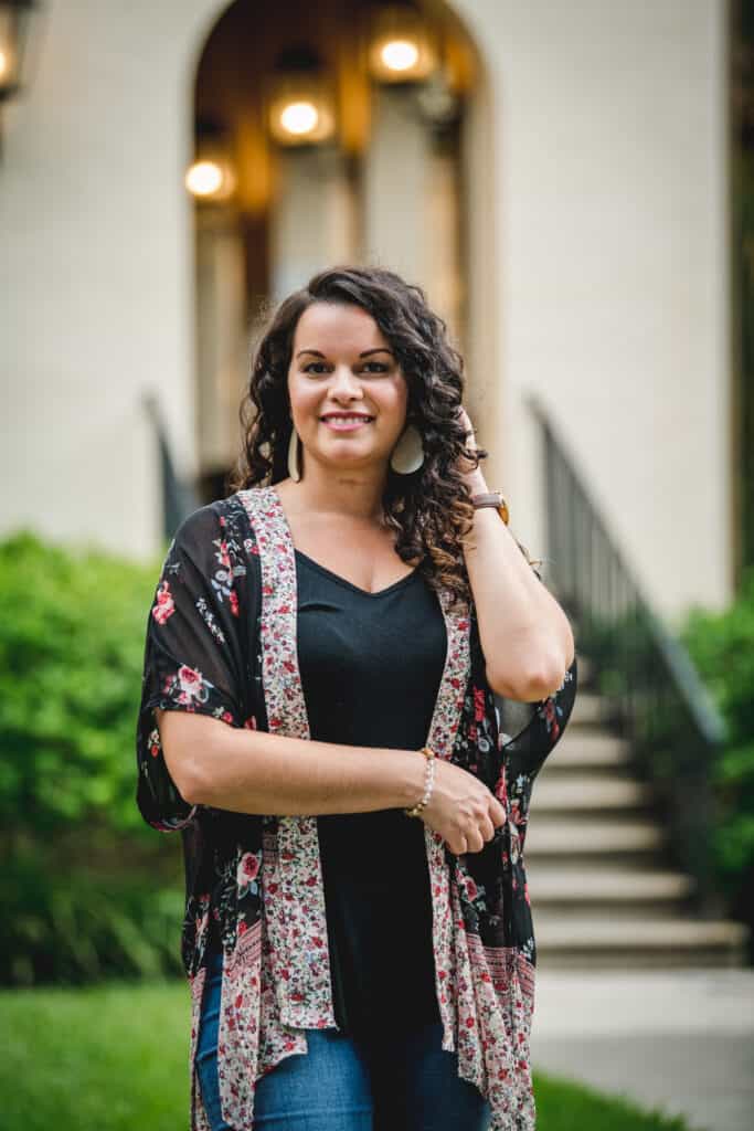 Curly wavy hair expert clean living beauty blogger Delilah Orpi posing outside in a garden with hand in hair