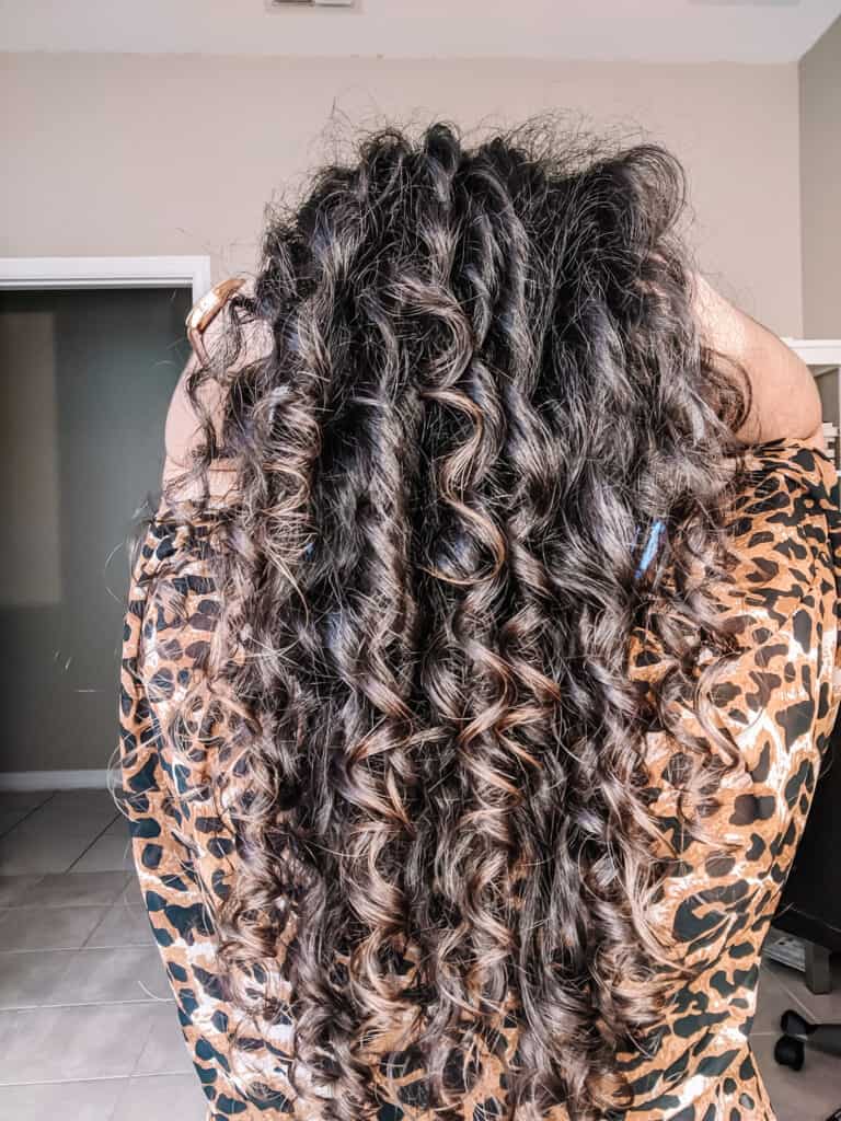 Back of Delilah's head with her hand holding her long healthy curls