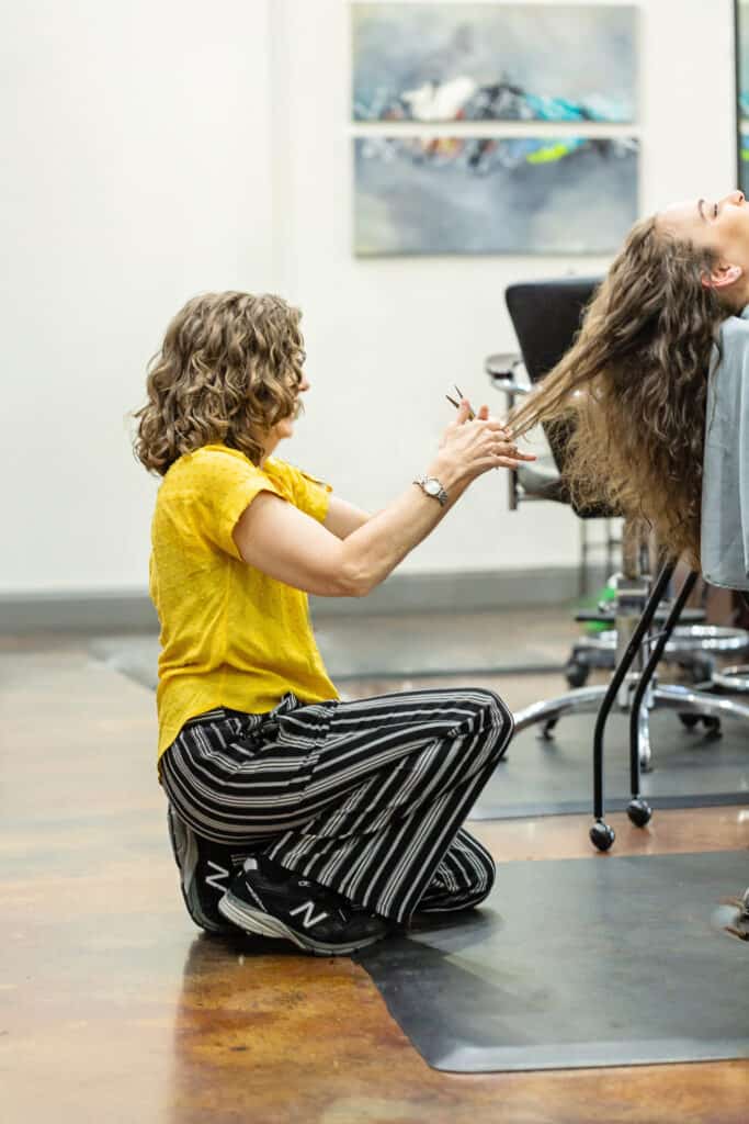 Laurie Cain Curl Specialist Holistic Enchilada team working on cutting a client's hair bend down